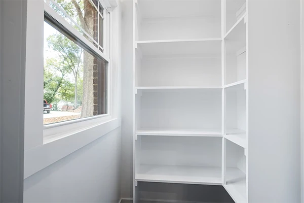 Bright and minimalist interior with white shelves and a sunny window view outdoors