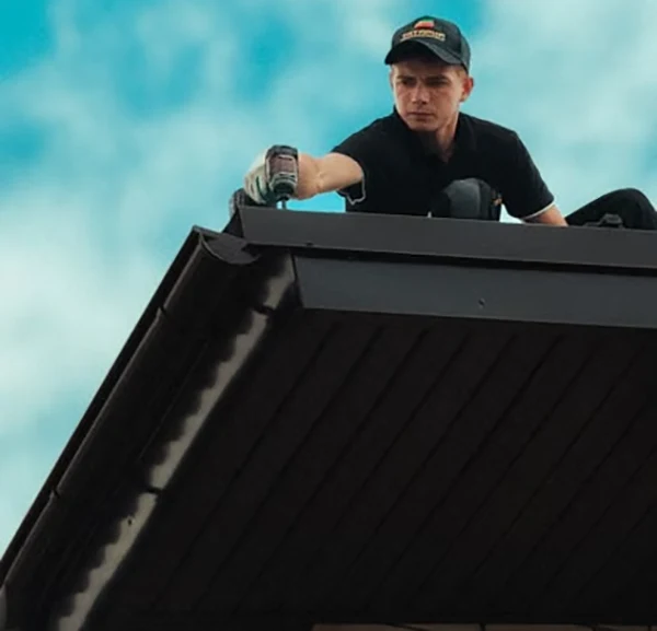 Roofer working diligently on a house roof under a bright blue sky Professional roofing maintenance in progress