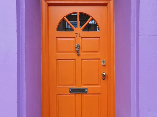 a beautiful house front door in a beautiful brown color and a purple wall beside it