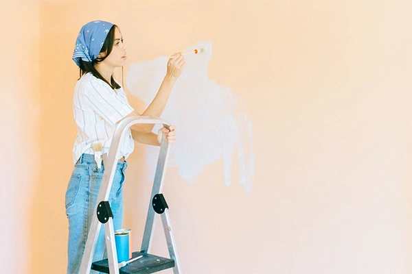 a girl painting the wall with face color