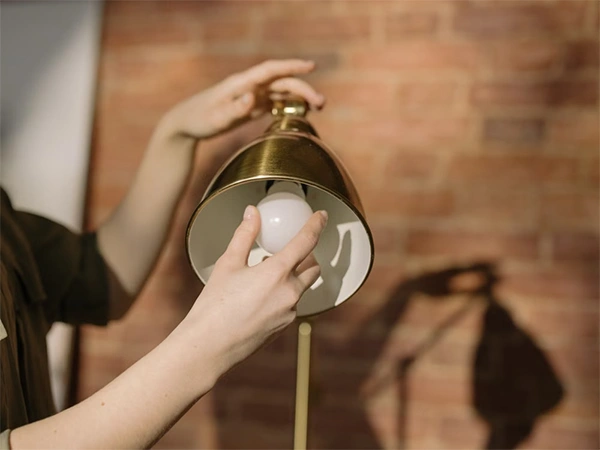 a persons hand fixing the light bulb in a lamp