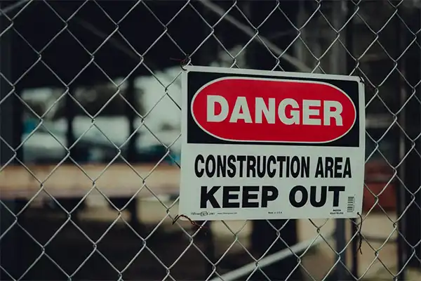 A warning sign board over a fence with the written message DANGER CONSTRUCTION AREA KEEP OUT